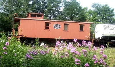 a train car sitting in a field of flowers at Vintage Caboose Rental in Historic Small Town near Springfield, Massachusetts in Chester