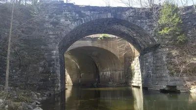 a stone bridge with two arches over a river at Vintage Caboose Rental in Historic Small Town near Springfield, Massachusetts in Chester