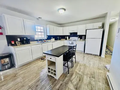 a kitchen with white cabinets and a black counter top at Newly renovated home, firepit, game room, grill in Tobyhanna