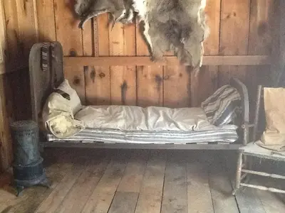 a small bed in a room with a wooden wall at Rustic Cabin Retreat on the Ten Mile River in Narrowsburg, New York in Narrowsburg