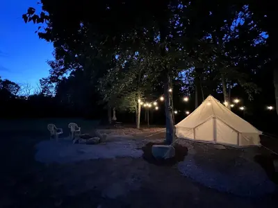 a white tent in a park at night at Lovely Bell Tent for Memorable Glamping Weekends in Conneticut
