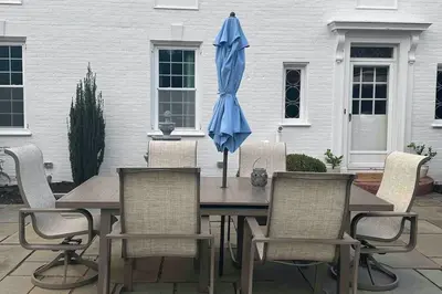 a blue umbrella sitting on a wooden table with chairs at Luxury Estate Elegant Private The White Lion Manor in Middletown