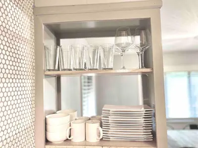 a cupboard with glasses and plates and wine glasses at Romantic Chalet Hot Tub Near Hunter Mountain in Tannersville