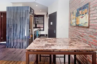 a kitchen with a wooden table and a brick wall at The Ideal II Vibe 8558 in New York