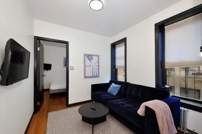 a living room with a blue couch and a tv at The Gram V Vibe 8615 in New York
