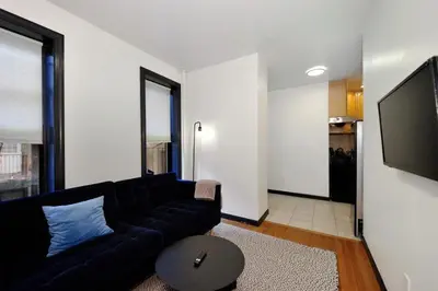 a living room with a black couch and a flat screen tv at The Gram V Vibe 8615 in New York