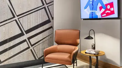a room with a chair and a tv on a wall at The Vibe on 5th Vibe 8750 in New York
