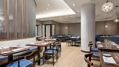 a restaurant with wooden tables and blue chairs at The Vibe on 5th IV Vibe 8753 in New York