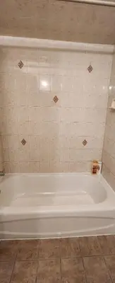 a white bath tub in a bathroom with tiles at Gold queen 4A in Newark