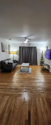 a living room with a couch and a table on a wooden floor at Happiness queen room 3 in Newark