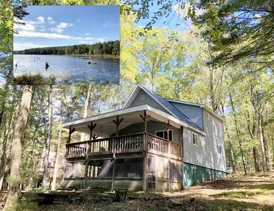 a large house with a deck in the woods at Beautiful Lakefront Chalet in the Poconos! in Hawley