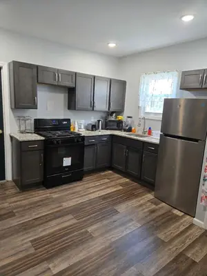 a kitchen with stainless steel appliances and wooden floors at Lemon king room 4 in Newark