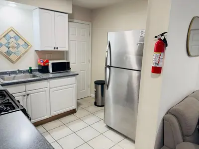 a kitchen with a stainless steel refrigerator and white cabinets at Cosy Bedroom 6 minutes to EWR Prudential Hotels Pen station in Newark