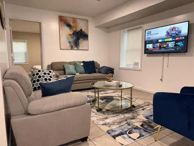 a living room with two couches and a flat screen tv at Cosy Bedroom 6 minutes to EWR Prudential Hotels Pen station in Newark