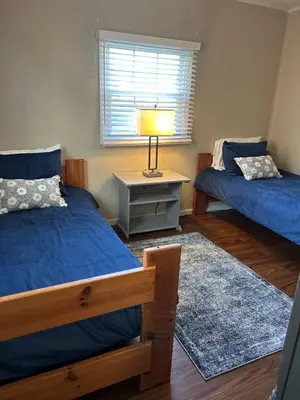 a bedroom with two beds and a table with a lamp at Charming Cottage with fenced yard in convenient location in Longmeadow