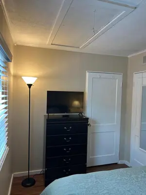 a bedroom with a bed and a dresser with a television at Charming Cottage with fenced yard in convenient location in Longmeadow