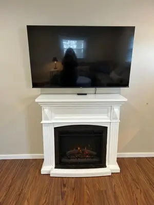 a living room with a fireplace with a tv on top at Charming Cottage with fenced yard in convenient location in Longmeadow