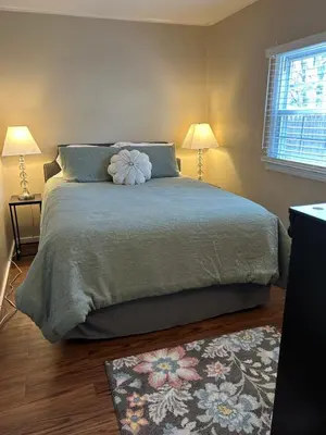 a bedroom with a bed with two lamps and a rug at Charming Cottage with fenced yard in convenient location in Longmeadow