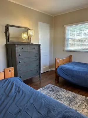 a bedroom with two beds and a dresser with a mirror at Charming Cottage with fenced yard in convenient location in Longmeadow