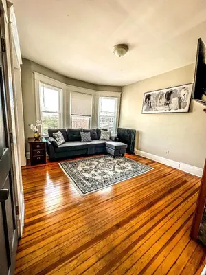 a living room with a couch and a wooden floor at The Red House Albany NY 4 Bedroom Private Apartment in Albany
