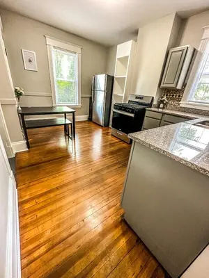 a kitchen with a hard wood floor and stainless steel appliances at The Red House Albany NY 4 Bedroom Private Apartment in Albany