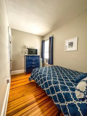 a bedroom with a bed and a dresser and a television at The Red House Albany NY 4 Bedroom Private Apartment in Albany