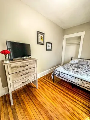 a bedroom with a bed and a dresser with a television at The Red House Albany NY 4 Bedroom Private Apartment in Albany
