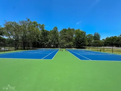 a couple of tennis courts with trees in the background at 3BR Home w Outdoor Fun Lake Fire Pit Games Grill in Tobyhanna