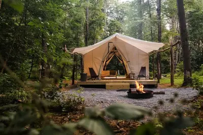 a tent in the middle of a forest with a fire at Classic Safari Tent in the Heart of the Adirondack Wilderness, near Lake George, New York in Corinth