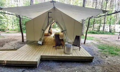 a tent with two chairs on a wooden deck at Classic Safari Tent in the Heart of the Adirondack Wilderness, near Lake George, New York in Corinth