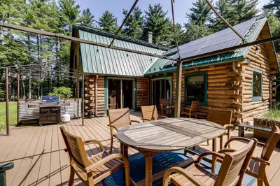 a patio with a table and chairs and a log cabin at 3 Mi to UMass Amherst Peaceful New England Cabin in Sunderland