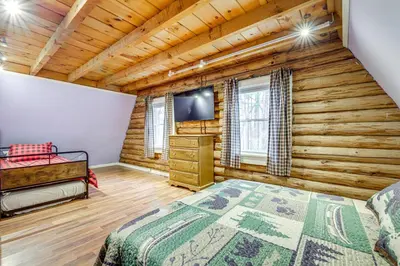 a log cabin bedroom with a bed and a flat screen tv at 3 Mi to UMass Amherst Peaceful New England Cabin in Sunderland