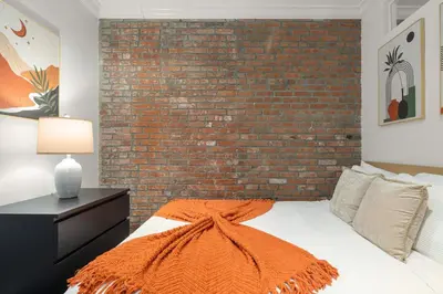 a bedroom with a brick wall and a bed at Explore NYC! Cozy 2BR in Prime Location in New York