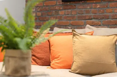a couch with pillows and a brick wall at Explore NYC! Cozy 2BR in Prime Location in New York