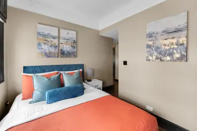a bedroom with a bed with orange and blue pillows at NYC Apartment in The Best Location! Walking Distance to Everything! in New York