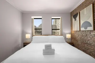 a bedroom with a large white bed with two windows at Stylish NYC Retreat Near Top Attractions in New York