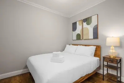 a white bedroom with a white bed and a lamp at Stylish NYC Retreat Near Top Attractions in New York
