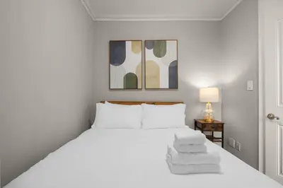 a white bedroom with a bed with towels on it at Stylish NYC Retreat Near Top Attractions in New York