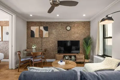 a living room with a television and a brick wall at Stylish NYC Retreat Near Top Attractions in New York