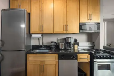 a kitchen with wooden cabinets and a stainless steel refrigerator at Stylish NYC Retreat Near Top Attractions in New York