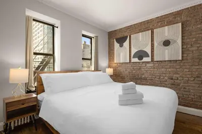 a bedroom with a white bed and a brick wall at Stylish NYC Retreat Near Top Attractions in New York