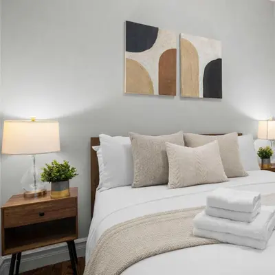 a bedroom with a white bed with three paintings on the wall at Modern Manhattan Haven Near Everything in New York