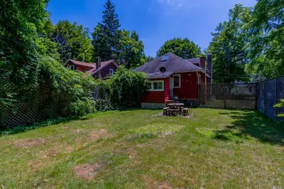 a yard with a red house and a fence at 1920s Phoenicia Bungalow with Vintage Furnishings, Sauna, Fireplace, & Fenced Backyard in Phoenicia