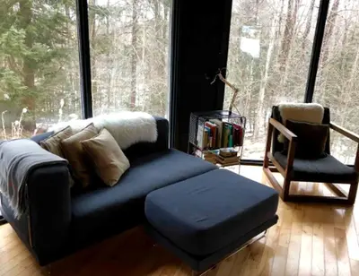 a living room with a blue couch and a chair at Imaginative Octogonal Glass Treehouse on Seven Private Acres near Great Barrington, MA in Great Barrington
