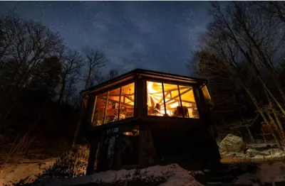 a glass house in the snow at night at Imaginative Octogonal Glass Treehouse on Seven Private Acres near Great Barrington, MA in Great Barrington