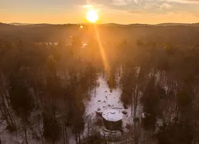 an aerial view of a house in a forest at sunset at Imaginative Octogonal Glass Treehouse on Seven Private Acres near Great Barrington, MA in Great Barrington