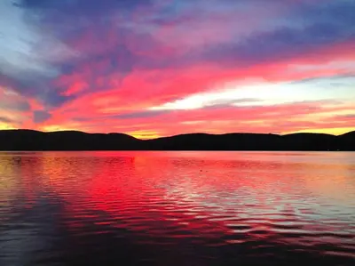 a sunset over a large body of water at Charming Cabin with Serene Lake Views for a Family Getaway near Pittsfield, Massachusetts in Pittsfield