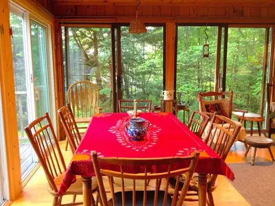 a dining room with a red table and chairs at Charming Cabin with Serene Lake Views for a Family Getaway near Pittsfield, Massachusetts in Pittsfield