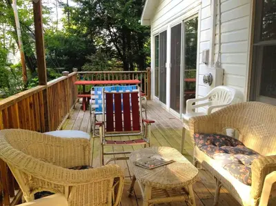 a porch with wicker chairs and tables on a house at Charming Cabin with Serene Lake Views for a Family Getaway near Pittsfield, Massachusetts in Pittsfield