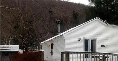 a white house with a fence in front of it at Spacious Cabin Rental next to Balsam Mountain in Upstate New York in Big Indian